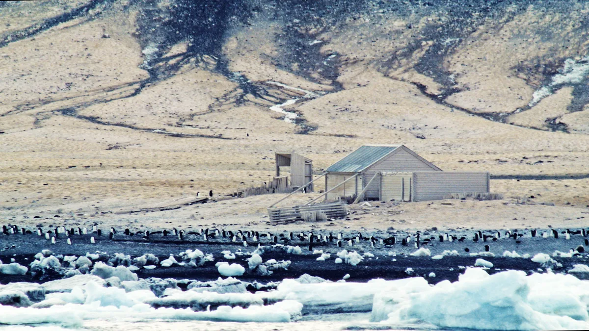 Borchgrevink's hut on the cobble spit at Cape Adare, with the Adare Peninsula in the background
